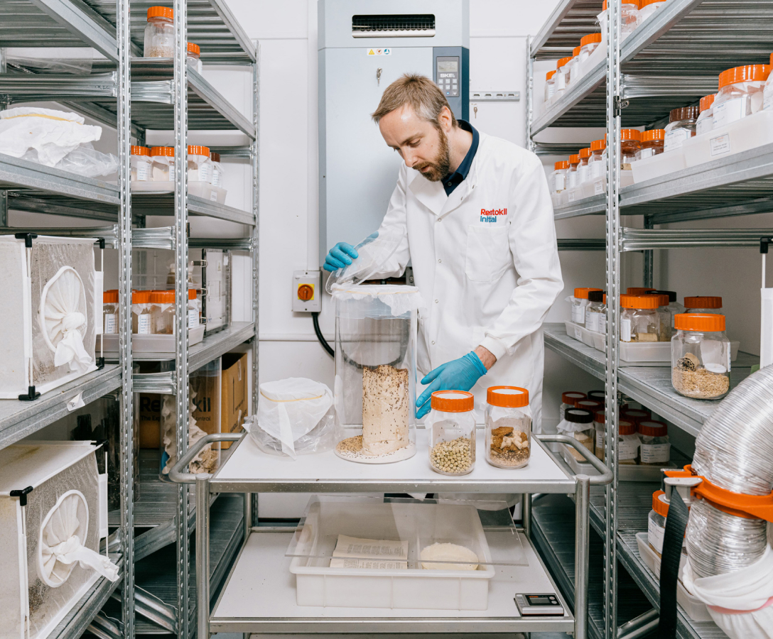 A man wearing a lab coat and gloves working in a laboratory with lots of specimen jars