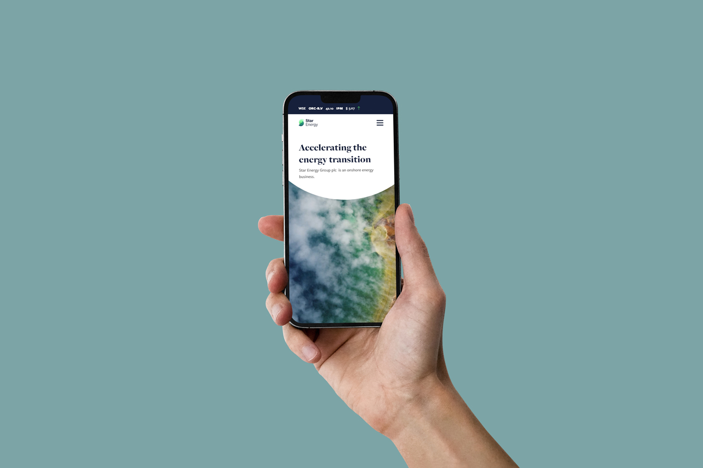 A hand holds a mobile phone that shows a page from a website