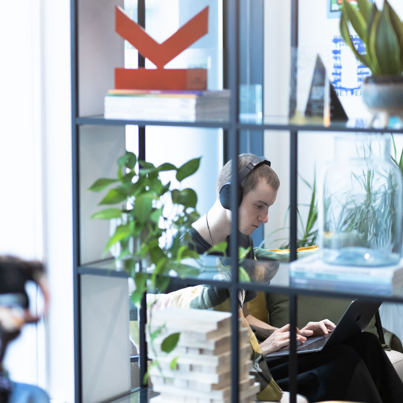 A man sits in a studio working on a laptop with headphones on