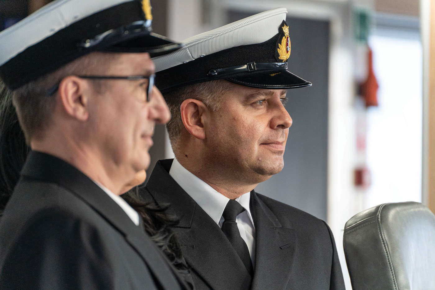 A close up of two men wearing Captain's uniforms looking off into the distance