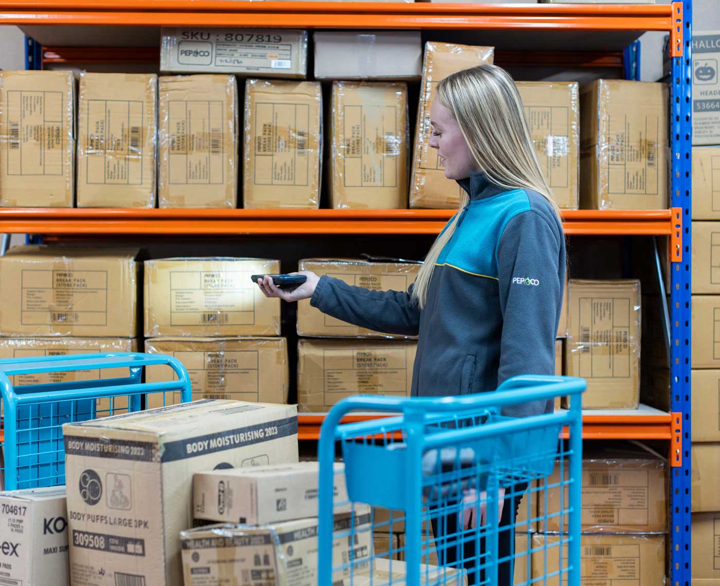 An female employee of Pepco working in a storage warehouse scans a barcode on the site of a box