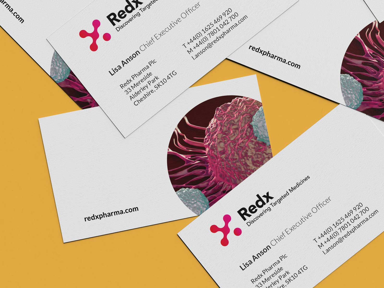 A pile of business cards laying on a table showing the Redx pharma brand and imagery